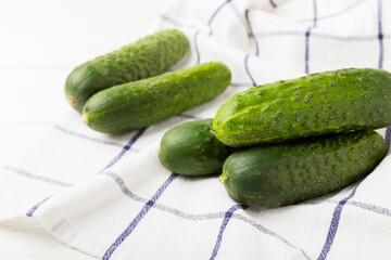 Fresh cucumbers on white texture wood. Vegetarian organic vegetables.Ingredient for salad. Healthy food.Copy space.Place for text