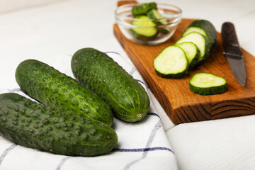 Fresh organic cucumbers on a white wooden table.Cucumber slices. Salad ingredient. Fresh vegetables. Vegan food. Healthy food. Fresh organic vegetables.