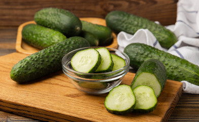 Fresh organic cucumbers on a brown wooden table.Cucumber slices. Salad ingredient. Fresh vegetables. Vegan food. Healthy food. Fresh organic vegetables.
