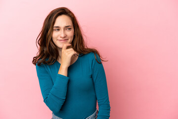 Young caucasian woman isolated on pink background looking to the side and smiling