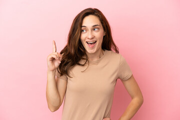 Young caucasian woman isolated on pink background thinking an idea pointing the finger up