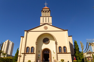 Fototapeta premium Vista frontal da Paróquia São Francisco de Assis - Diocese de Anápolis em Goiás com céu azul ao fundo.