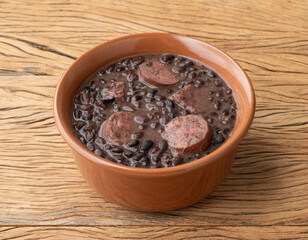 Traditional brazilian feijoada in a bowl over wooden table
