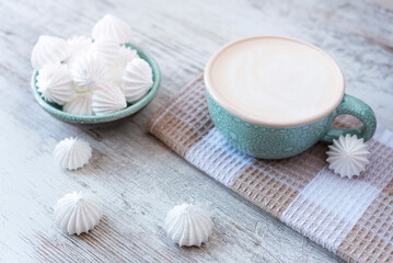 Fototapeta na wymiar Cup of coffee on the kitchen towel, bowl full of meringue on the rustic wooden background. Flat lay