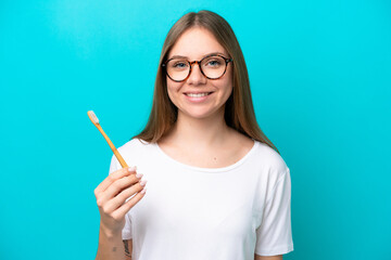 Young Lithuanian woman brushing teeth over isolated background smiling a lot