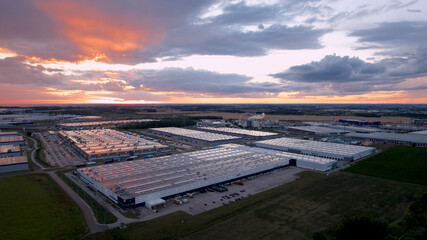 ogromne magazyny centra logistyczne o zachodzie słońca z drona
