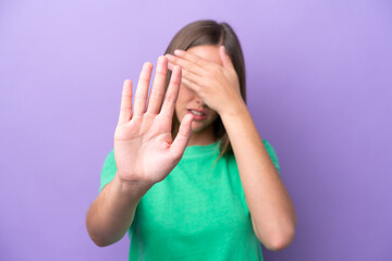 Young caucasian woman isolated on purple background making stop gesture and covering face