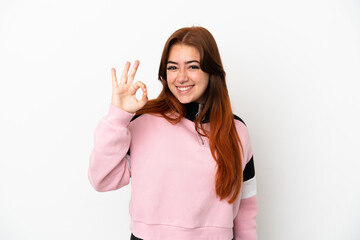 Young redhead woman isolated on white background showing ok sign with fingers