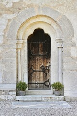 Ancient gothic style door. Rustic door with pretty medieval details and a stone wall.