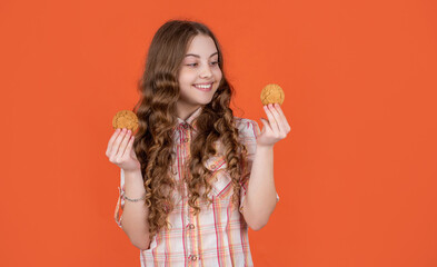 cheerful teen girl with oatmeal cookies on orange background
