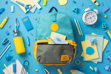 Back to school concept. Top view photo of open blue backpack with sticky note paper pens clips...