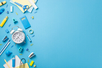 School concept. Top view photo of alarm clock plastic alphabet letters correction pen clip stapler eraser notebook adhesive tape calculator scissors ruler isolated blue background with copyspace