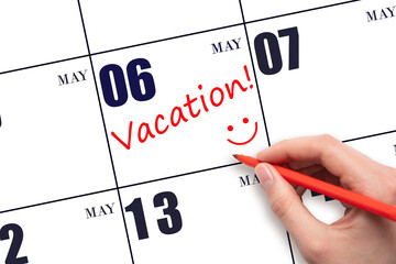 A hand writing a VACATION text and drawing a smiling face on a calendar date 6 May. Vacation...