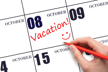 A hand writing a VACATION text and drawing a smiling face on a calendar date 8 October. Vacation planning concept.