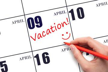 A hand writing a VACATION text and drawing a smiling face on a calendar date 9 April. Vacation...