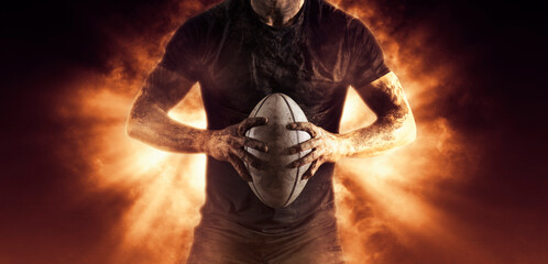 Rugby player holds ball on fire background