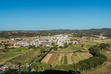 Fototapeta premium Agricultural fields and Alzejur village architecture in aerial view, PORTUGAL