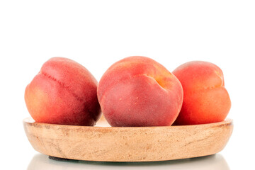 Three ripe red apricots on a wooden saucer, close-up, isolated on a white background.
