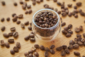 Coffee beans in a transparent bowl over a wood tablet with copy space.