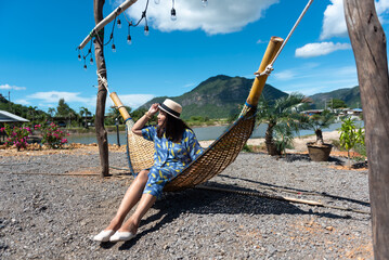 Young Asian woman relaxing on the cradle with mountain background.