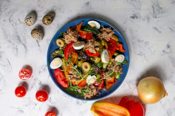 Healthy hearty salad of tuna, tomatoes, eggs, tuna, olives close-up in a bowl on the table. Salad Nicoise. French cuisine. View from above.