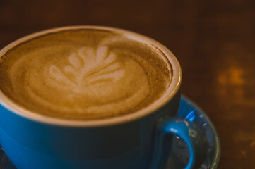 A blue cappuccino mug with a petal pattern on the foam. Minimalistic coffee mug concept.