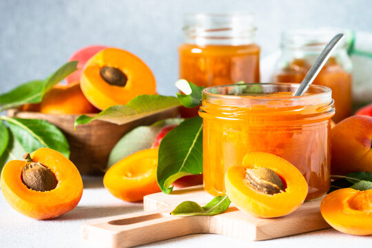 Apricot jam in glass jar, homemade preservation at white kitchen table.