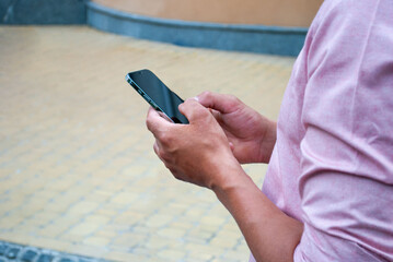 man's hand holding mobile phone and texting sms. Close up of man with smartphone