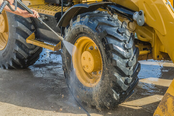 Washing a wheeled tractor at a car wash with a foam solution - obrazy, fototapety, plakaty