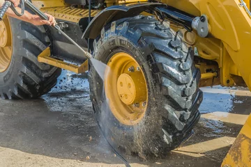 Photo sur Plexiglas Tracteur Laver un tracteur à roues dans un lave-auto avec une solution moussante