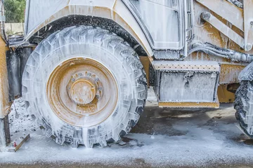 Türaufkleber Washing a wheeled tractor at a car wash with a foam solution © kvdkz