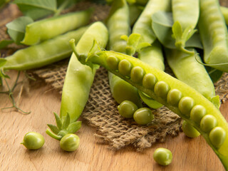 fresh peas and their pods on an old wooden table , rustic background with peas