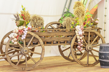 Wooden cart decorated with bunches of garlic, dry spikelets and handmade toy roosters. Vintage rustic ethnic style
