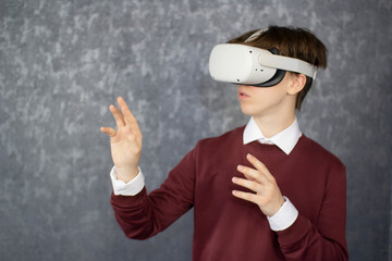 Teen male student use vr glasses and looks at empty copy space .Virtual gadgets for entertainment, work, free time and study. Virtual reality metaverse technology concept.