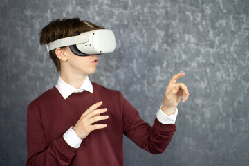 Teen male student use vr glasses and looks at empty copy space .Virtual gadgets for entertainment, work, free time and study. Virtual reality metaverse technology concept.