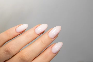 Tuinposter Beautiful nude manicure. Almond shaped nails. Nail design. Manicure with gel polish. Close-up of the hands of a young woman with a gentle nude manicure on the nails. Bright nails with gel polish. © Alina