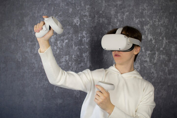 Young teenage student wearing virtual reality glasses on gray background