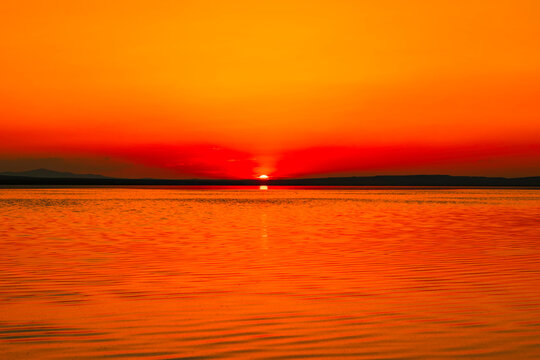 Orange sunset over the lake. Sunset or sunrise background or wallpaper photo