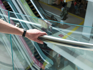 Man holding a hand rail in mall staircase closeup. Stock photo of the guy walking on the staircase...