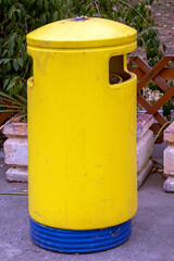Fototapeta na wymiar Yellow trash can on rural street road