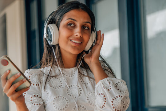 latin girl with headphones and mobile phone or smartphone listening to music