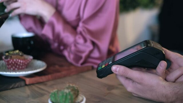 Video of close up of customer using her credit card to make payment with electronic reader in the restaurant.