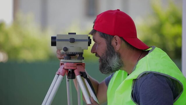 A man works with an optical level to level the landscape