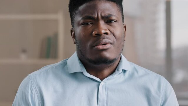 Close up portrait upset African American disappointed businessman leader entrepreneur guy man unpleasantly shocked looking at terrible thing dissatisfied mimic facial emotion feels aversion desperate