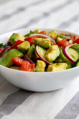 Homemade Organic Cucumber, Tomato and Avocado Salad in a Bowl, side view.