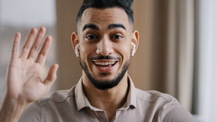 Happy young coach arab man blogger wears wireless earphones say hello at camera subscribers record...