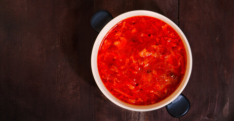 Black plate of borscht on a wooden table, top view. Traditional Ukrainian Russian hot soup. Beets, cabbage, carrots, potatoes, peppers, onions, dill, parsley, tomatoes, in meat or vegan broth. Banner