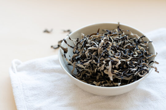 Dried mun mushrooms, Chinese traditional medicine and cuisine. Fungi ingredients in plate on beige background