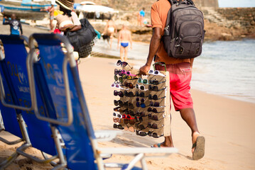 Street vendors walk on the sand of Porto da Barra beach
