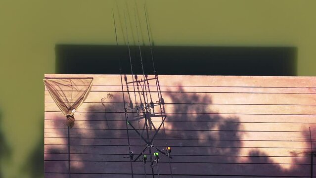 Close up fishing rods with rodpod and fishing net on a wood platform. Carpfising swim. Drone video footage.